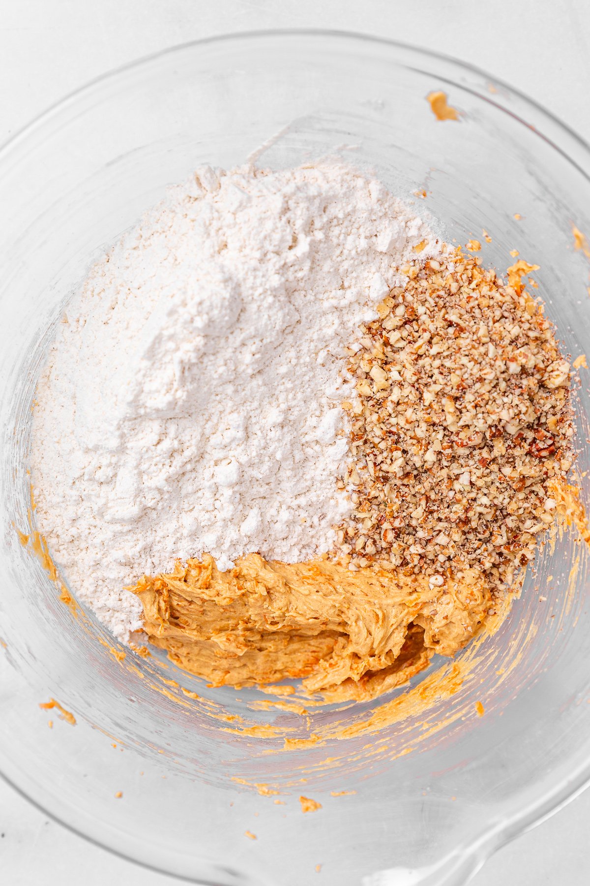 saladier avec pâte à cookies et ingrédients secs et noix concassées