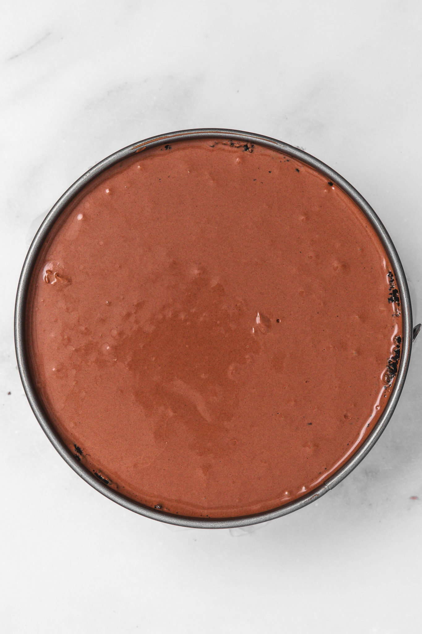 Nutella cheesecake batter poured into Oreo crust before baking