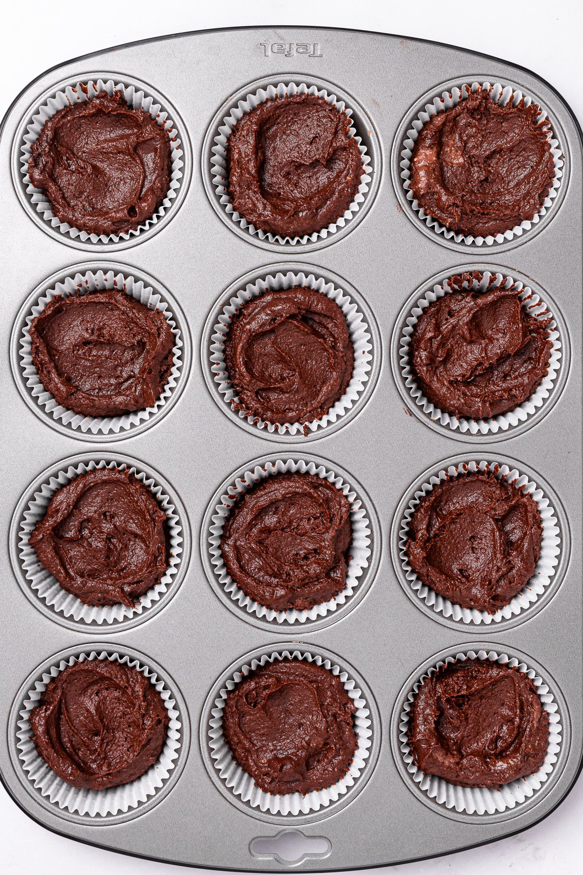 unbaked chocolate cupcake batter in lined muffin pan