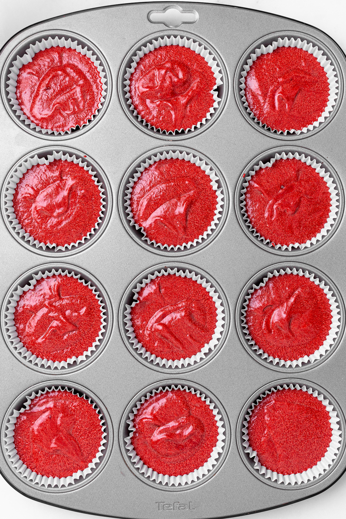 unbaked red velvet cupcake batter in lined muffin pan