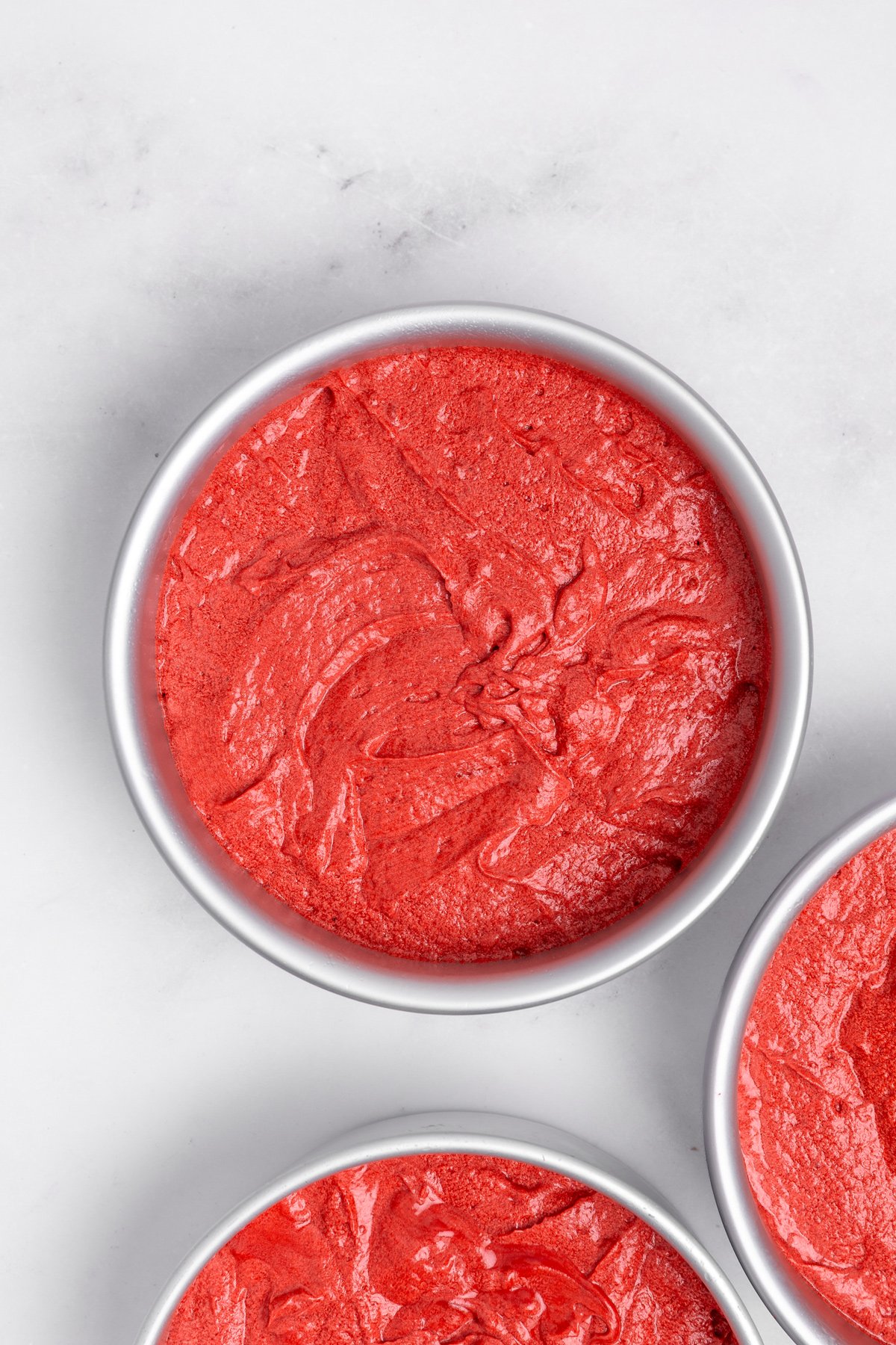 red velvet cake batter divided into three cake pans