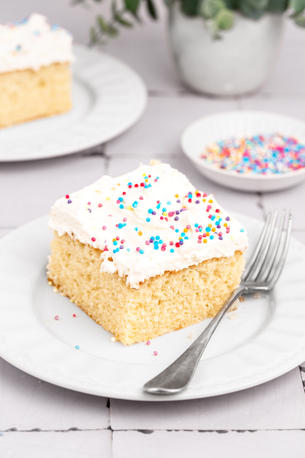 slice of vanilla sheet cake on plate with frosting