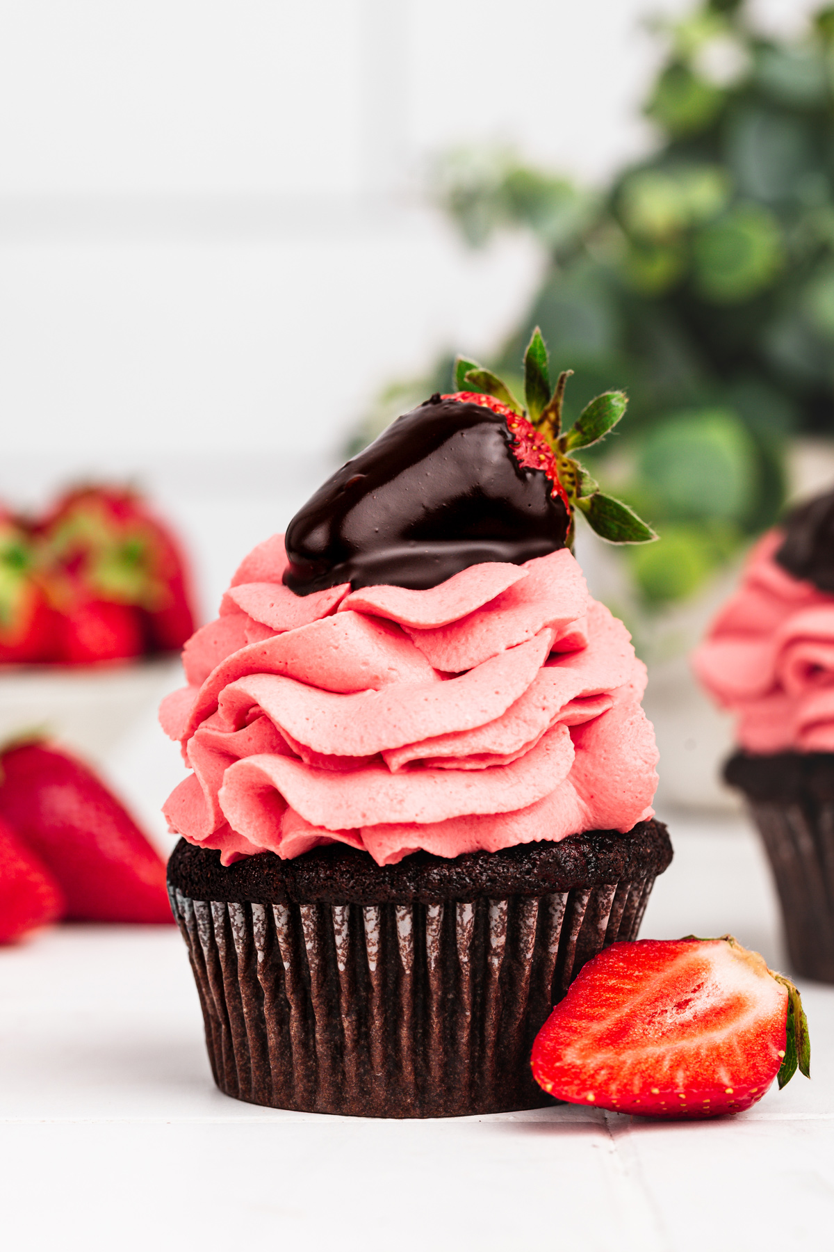 chocolate strawberry cupcakes with strawberry frosting on a table