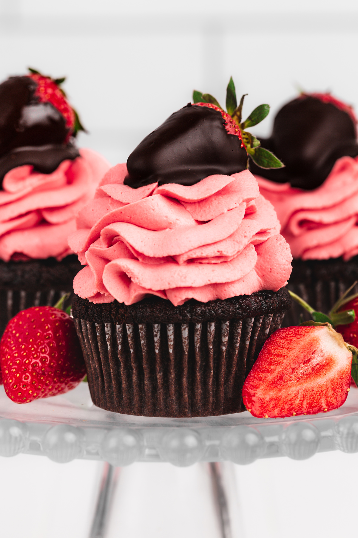chocolate strawberry cupcakes with strawberry frosting and chocolate-covered strawberries on a cake stand