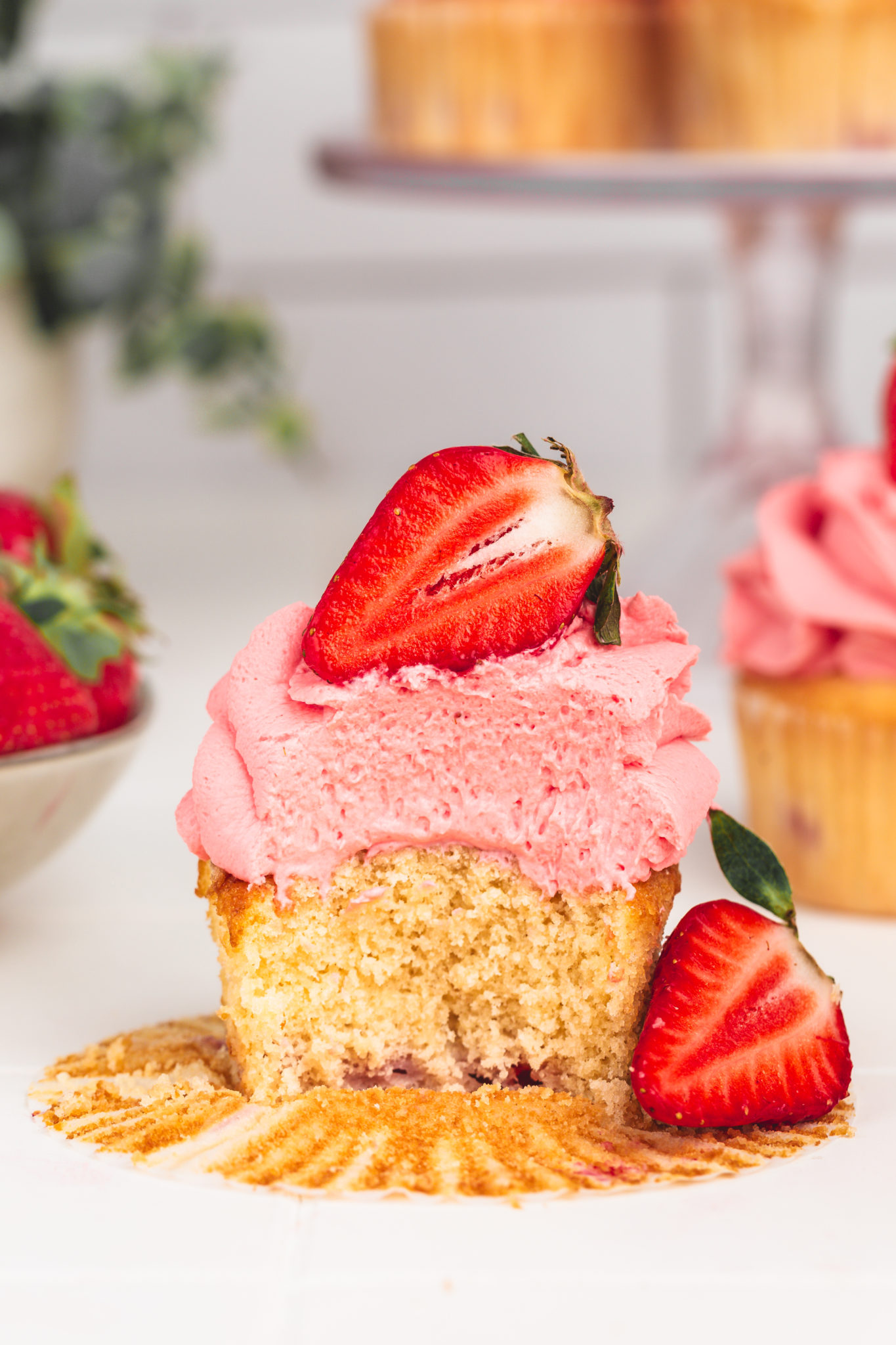 strawberry cupcake cut in half showing the soft vanilla crumb and strawberry pieces