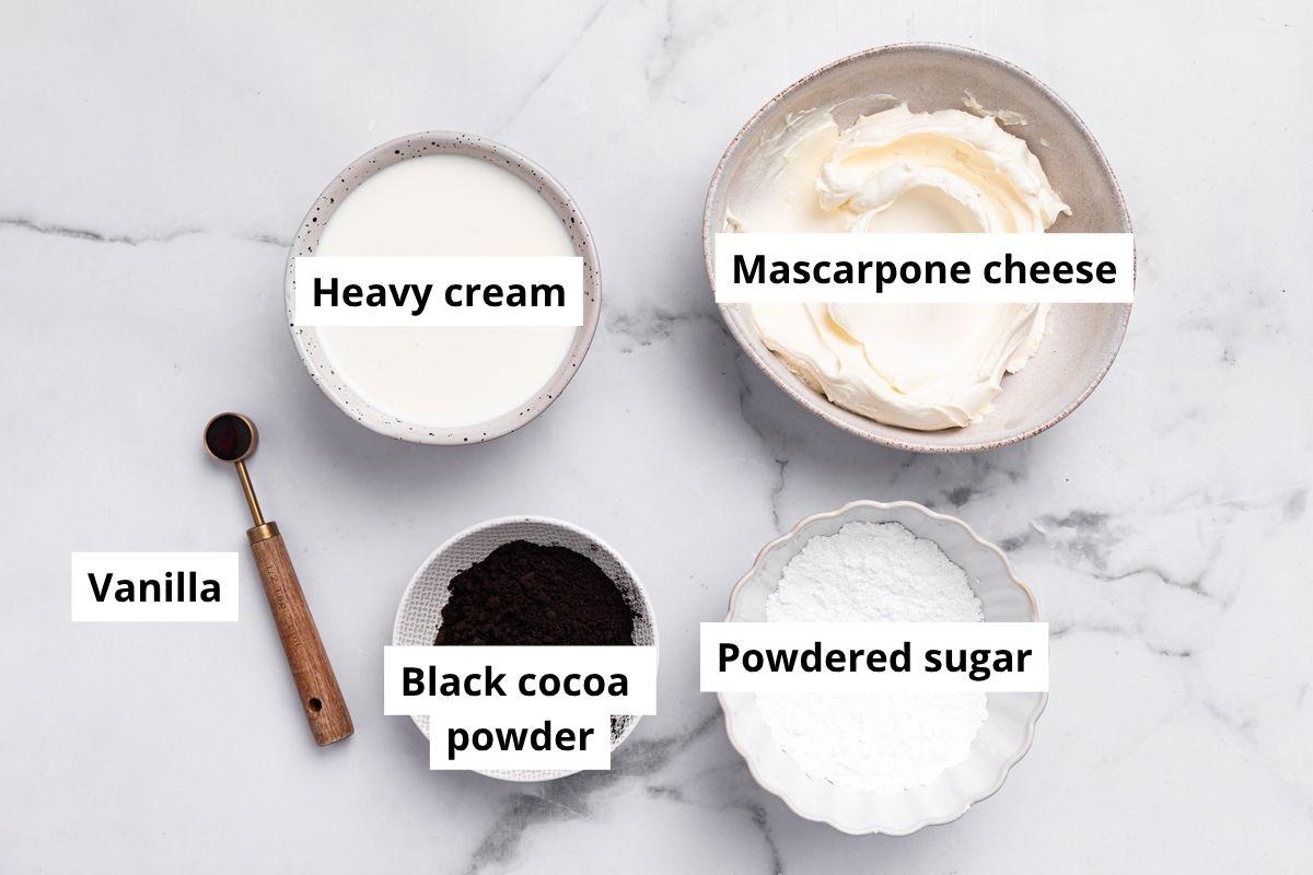 ingredients for black cocoa frosting including mascarpone, cream, powdered sugar and black cocoa powder