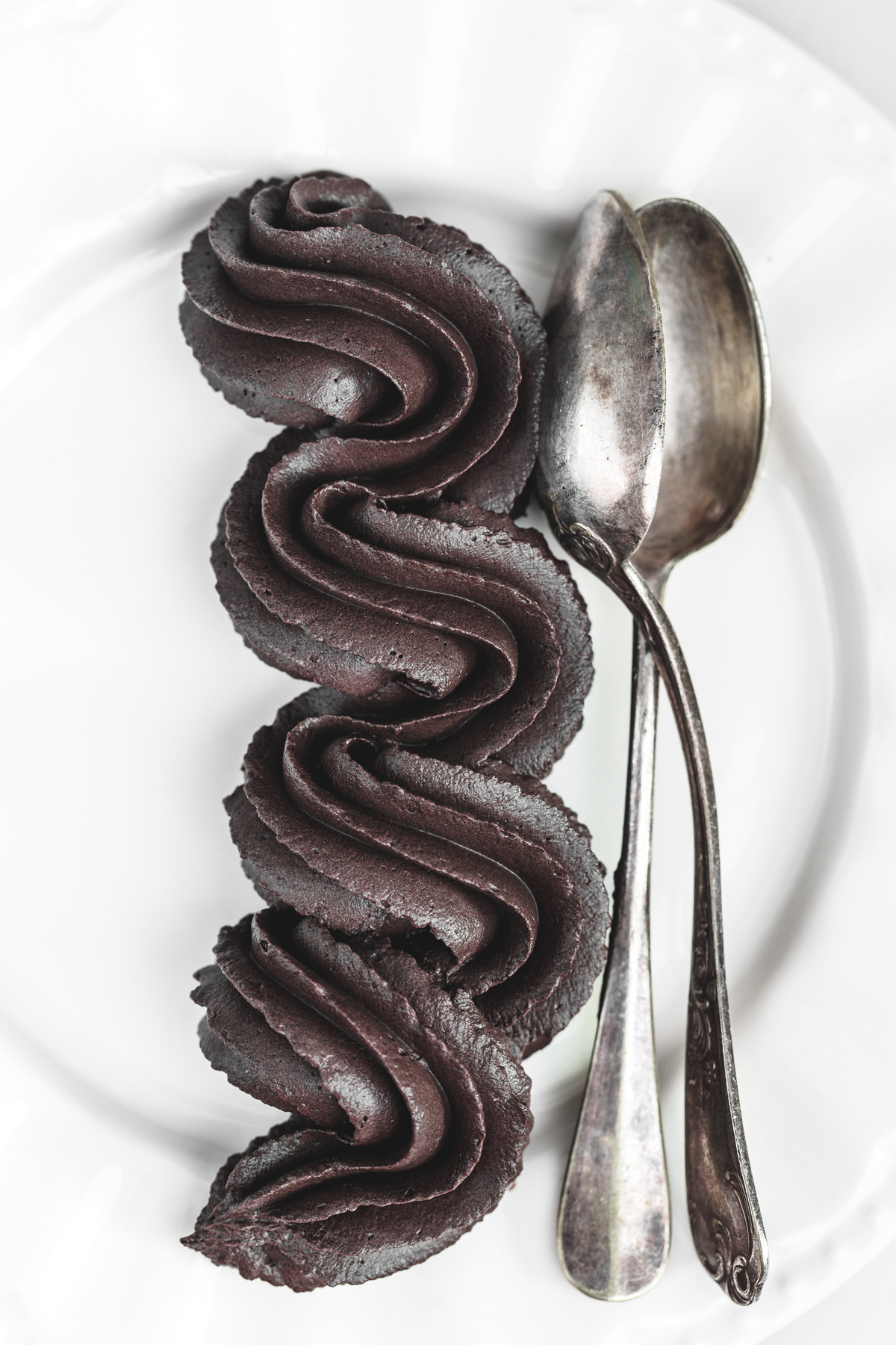 black cocoa frosting piped onto a plate with coffee spoons
