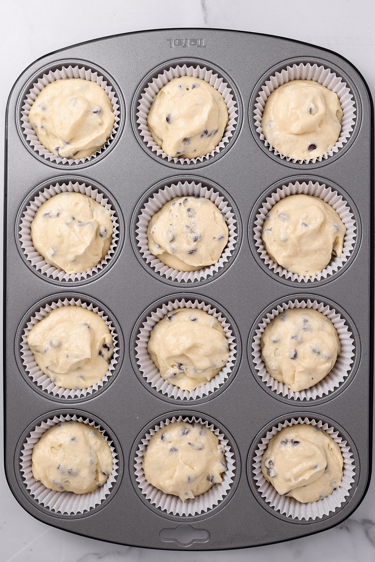 Cupcake pan filled with chocolate chip cupcake batter before baking