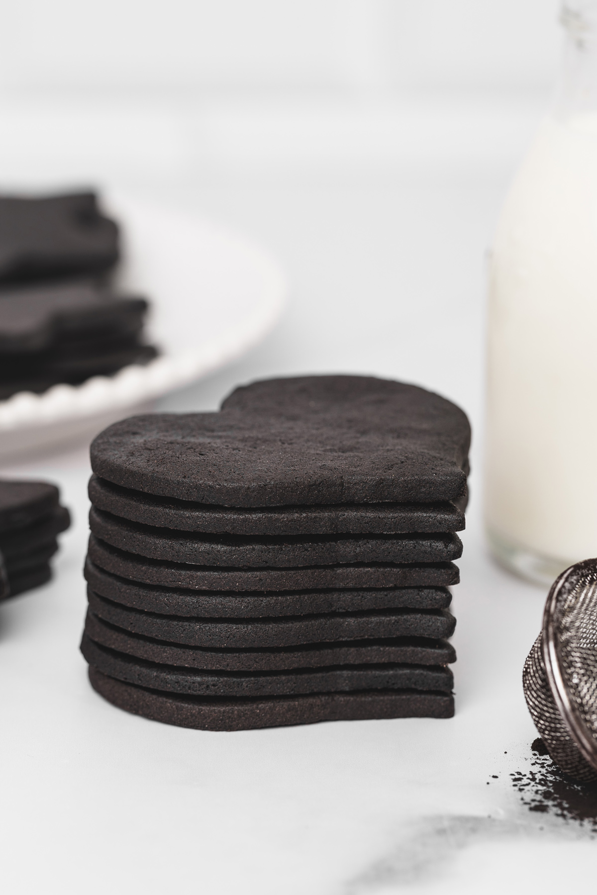 Stack of heart-shaped black cocoa cut out sugar cookies on a table