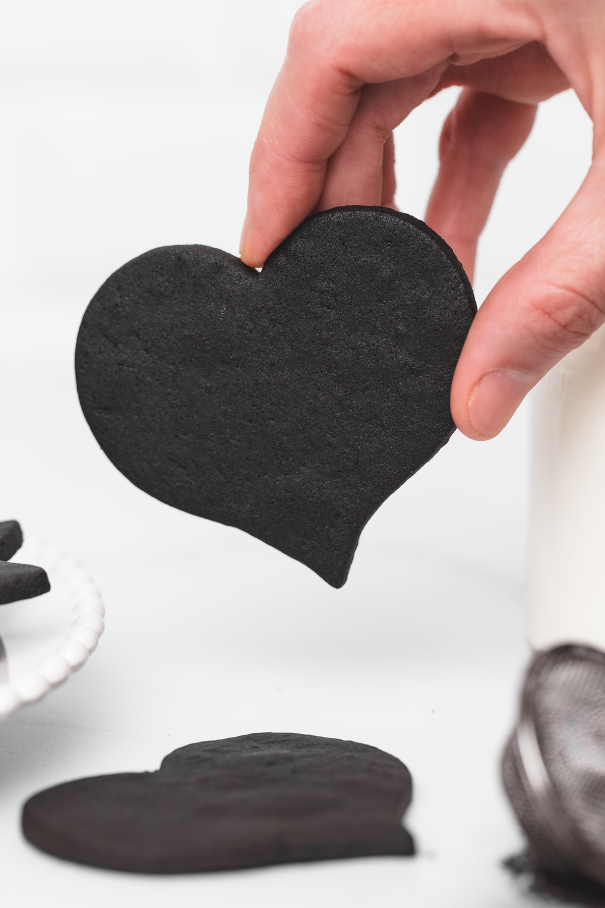 Black cocoa heart-shaped cut out cookie held by hand