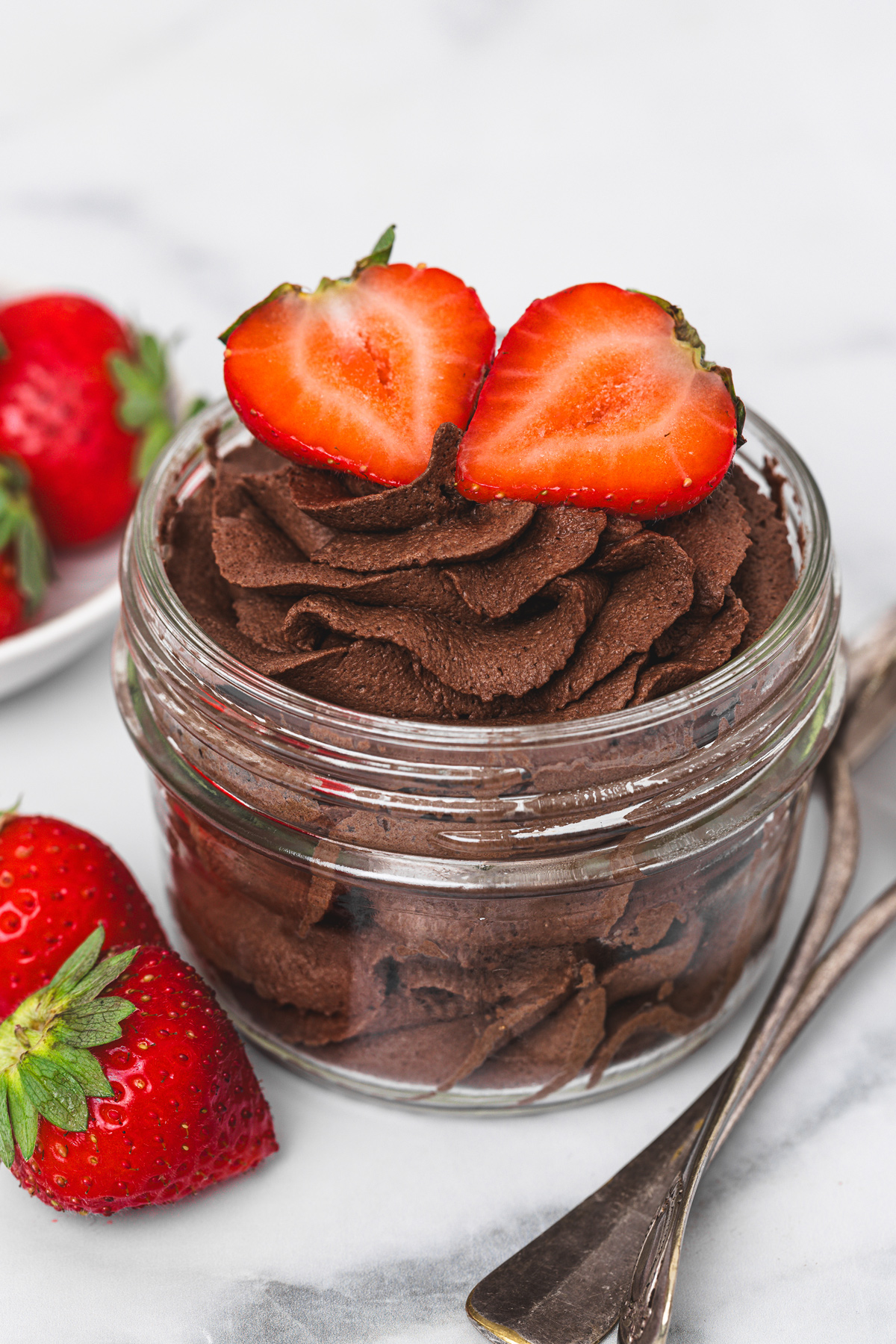 Chocolate whipped cream served in a glass jar topped with fresh strawberries